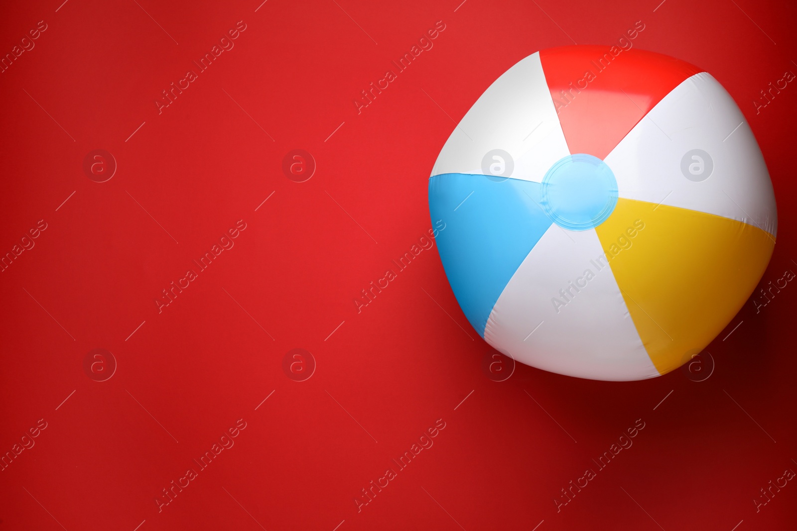 Photo of Bright beach ball on red background, top view. Space for text