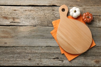 Cutting board, napkin and decorative pumpkins on old wooden table, top view. Space for text