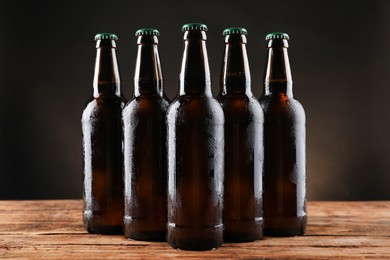 Many bottles of beer on wooden table against dark background