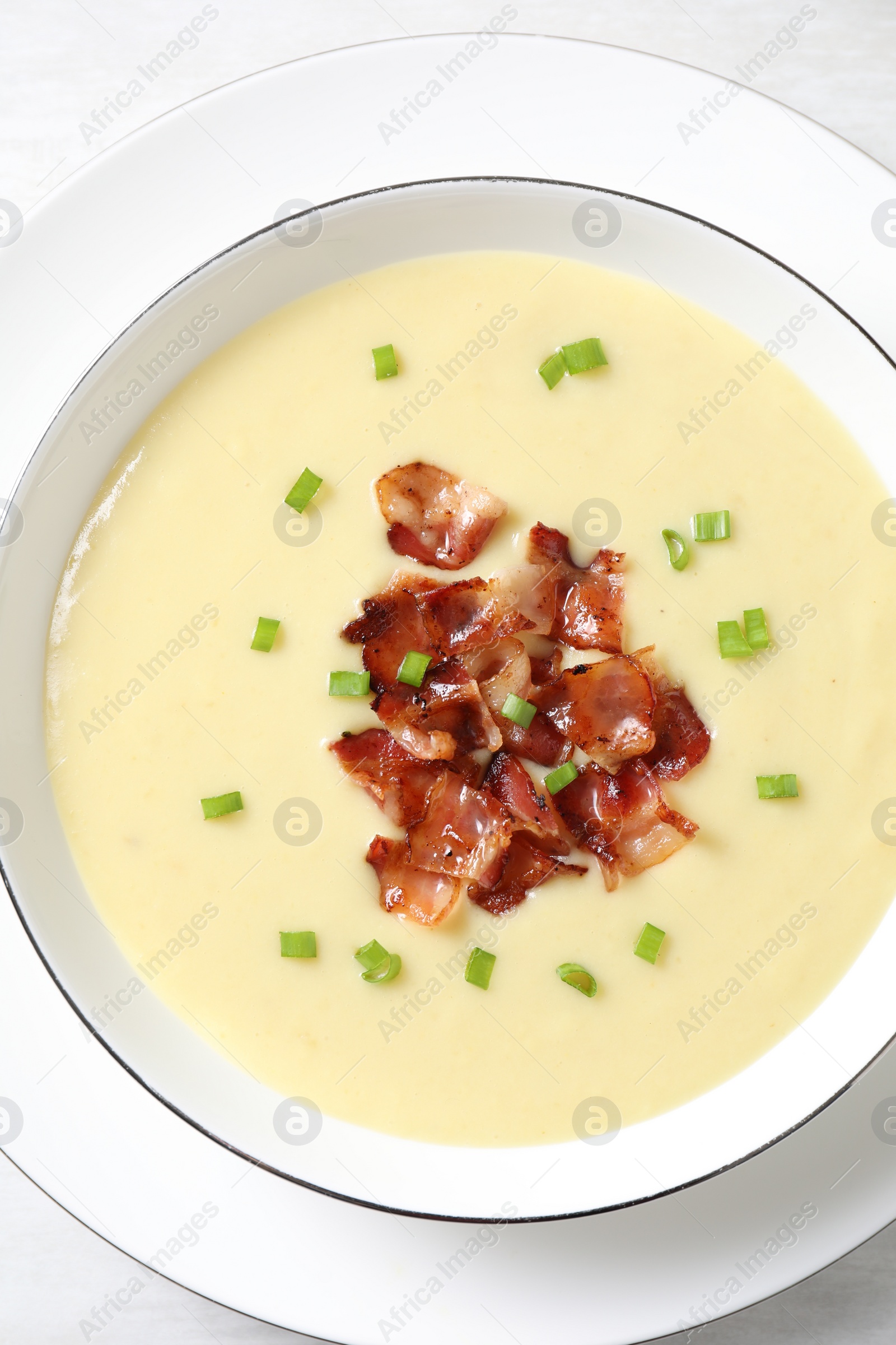 Photo of Tasty potato soup with bacon and green onion in bowl on white table, top view