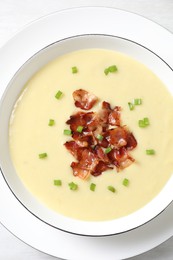 Tasty potato soup with bacon and green onion in bowl on white table, top view