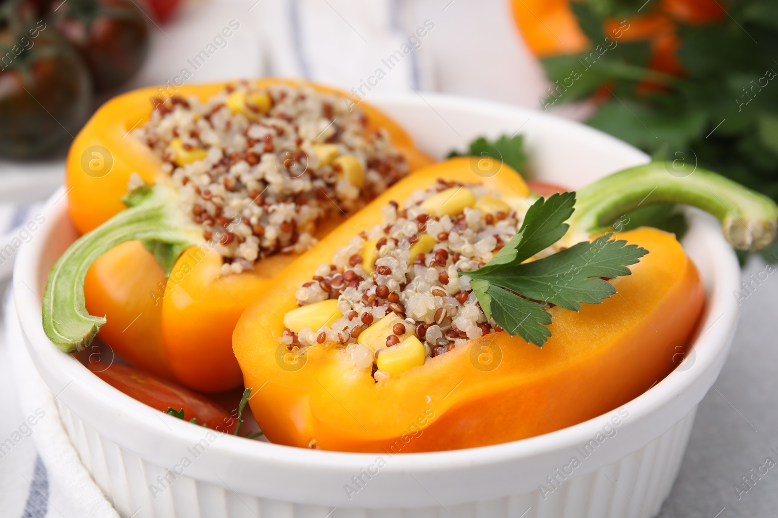 Photo of Quinoa stuffed bell pepper and parsley in bowl on light table, closeup