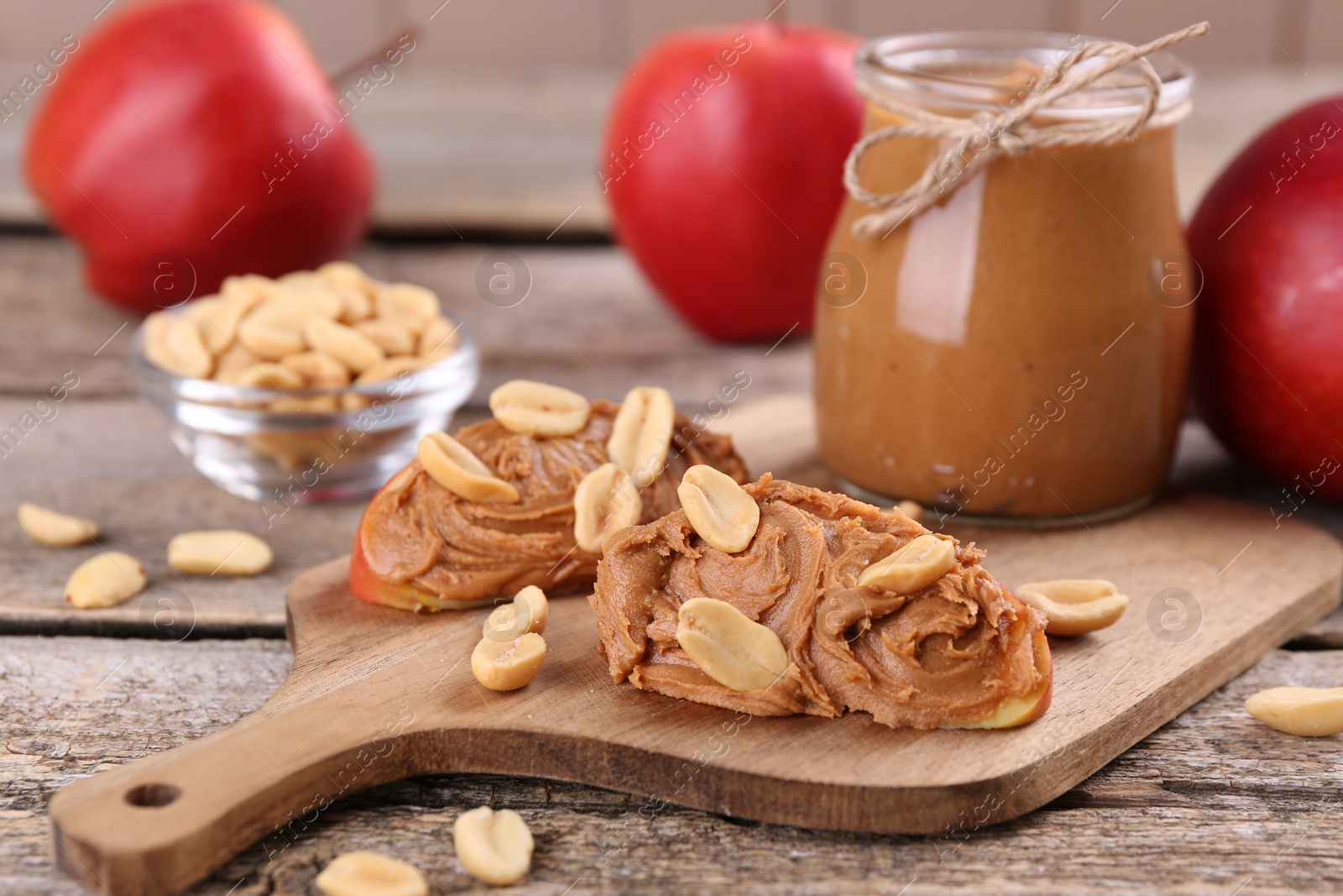 Photo of Fresh apples with peanut butter on wooden table