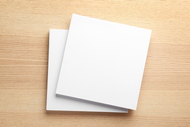 Photo of Stack of blank paper sheets for brochure on wooden background, top view. Mock up