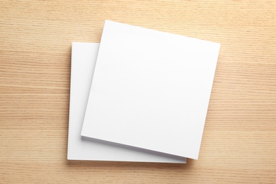 Stack of blank paper sheets for brochure on wooden background, top view. Mock up