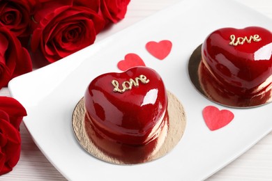 Photo of St. Valentine's Day. Delicious heart shaped cakes and roses on table, closeup