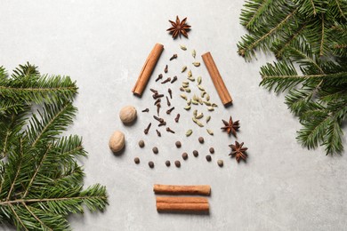 Photo of Christmas tree made of different spices and fir branches on light gray textured table, flat lay