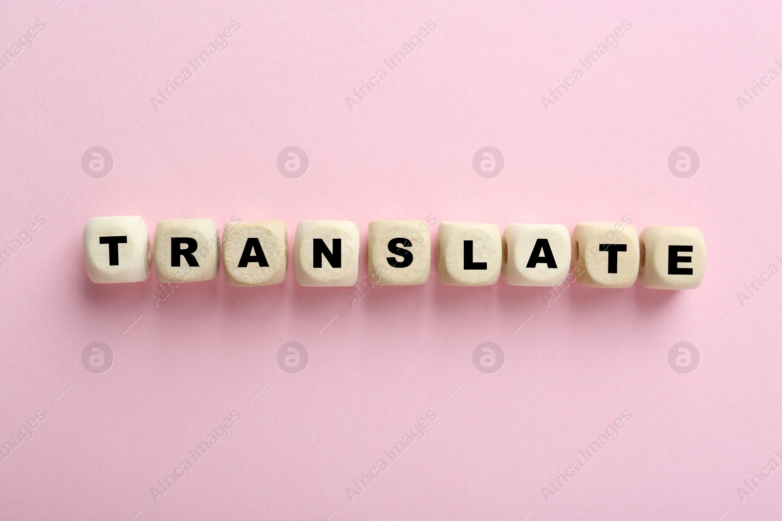 Photo of Cubes with word Translate on pink background, top view