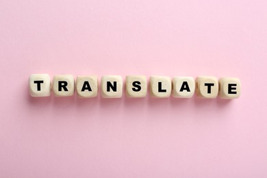 Cubes with word Translate on pink background, top view