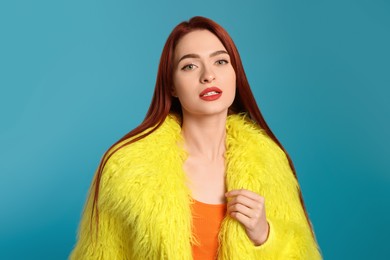 Stylish woman with red dyed hair on light blue background