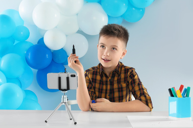 Photo of Cute little blogger with marker recording video at table