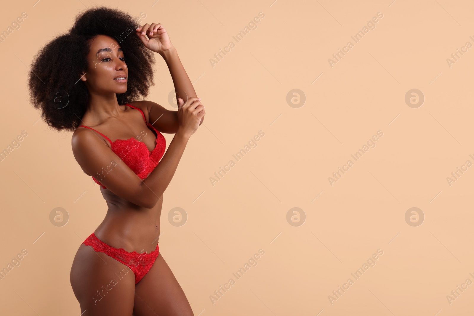 Photo of Beautiful woman in elegant red underwear on beige background, space for text