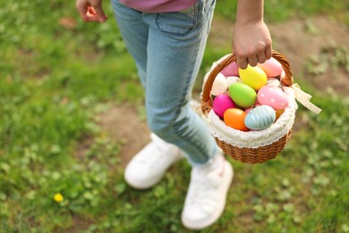 Photo of Easter celebration. Little girl holding basket with painted eggs outdoors, closeup