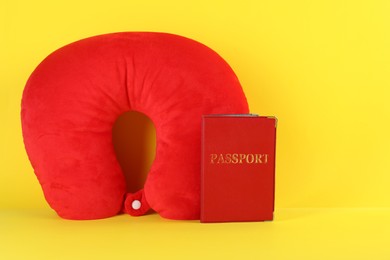 Photo of Red travel pillow and passport on yellow background