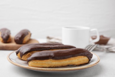 Photo of Delicious eclairs covered with chocolate on grey table, closeup