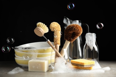 Photo of Cleaning supplies for dish washing and soap bubbles on black background