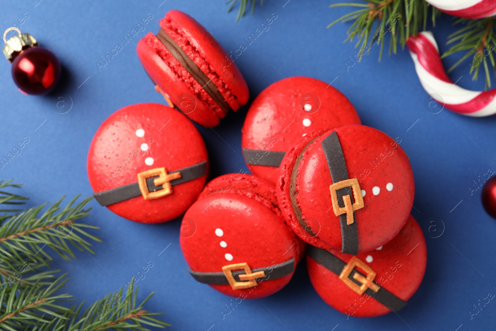 Photo of Pile of beautifully decorated Christmas macarons on blue background, flat lay