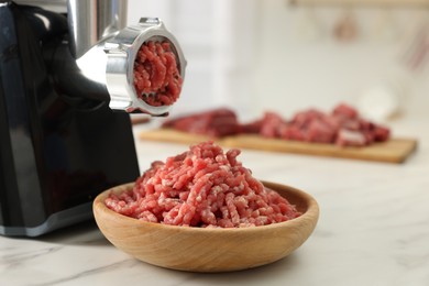 Photo of Electric meat grinder with minced beef on white marble table indoors, space for text
