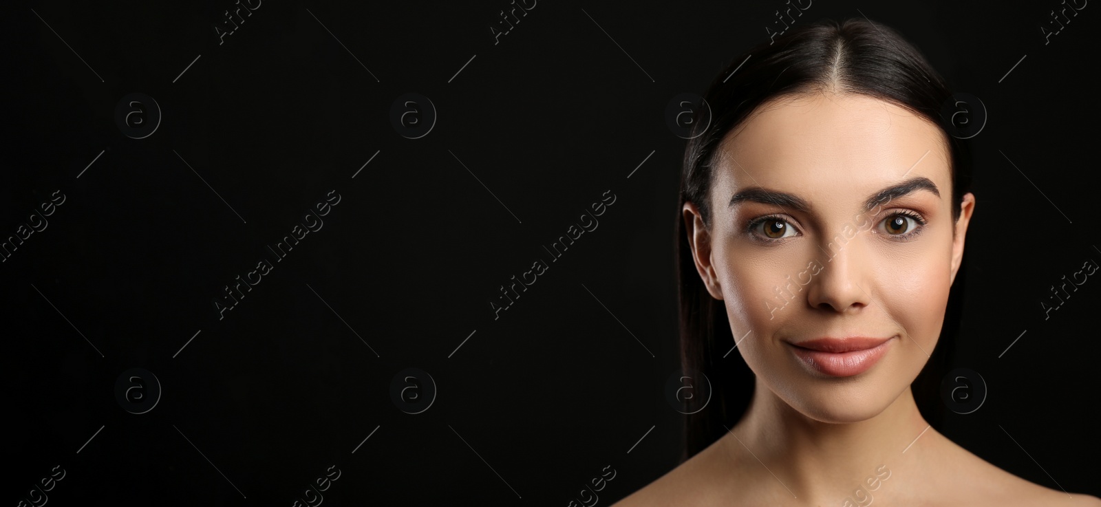 Photo of Portrait of happy young woman with beautiful black hair and charming smile on dark background, space for text