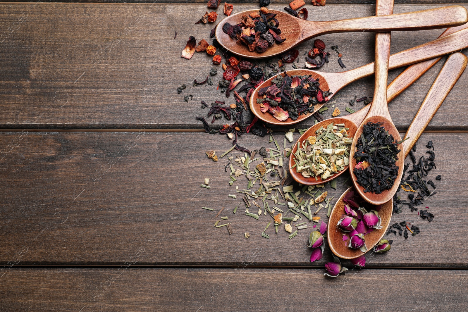 Photo of Flat lay composition with different teas and spoons on wooden table. Space for text