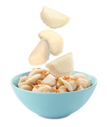 Image of Many tasty dumplings falling into bowl on white background