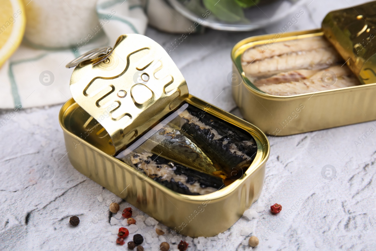 Photo of Open tin cans with mackerel fillets on light textured background