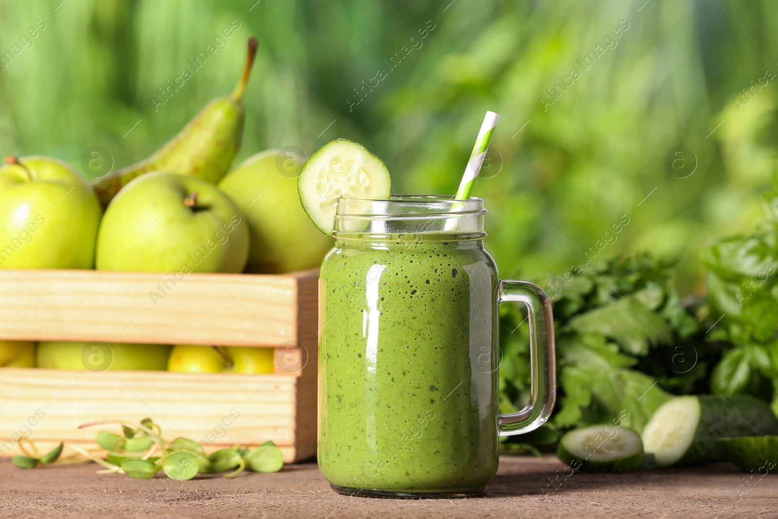 Photo of Mason jar of fresh green smoothie and ingredients on wooden table outdoors