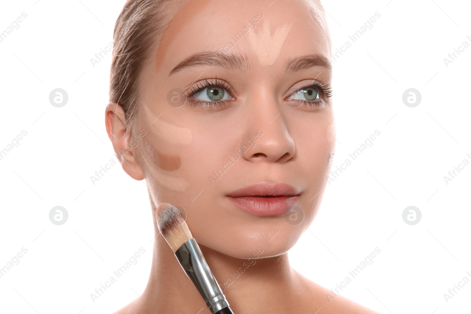 Photo of Young woman applying foundation on her face against white background