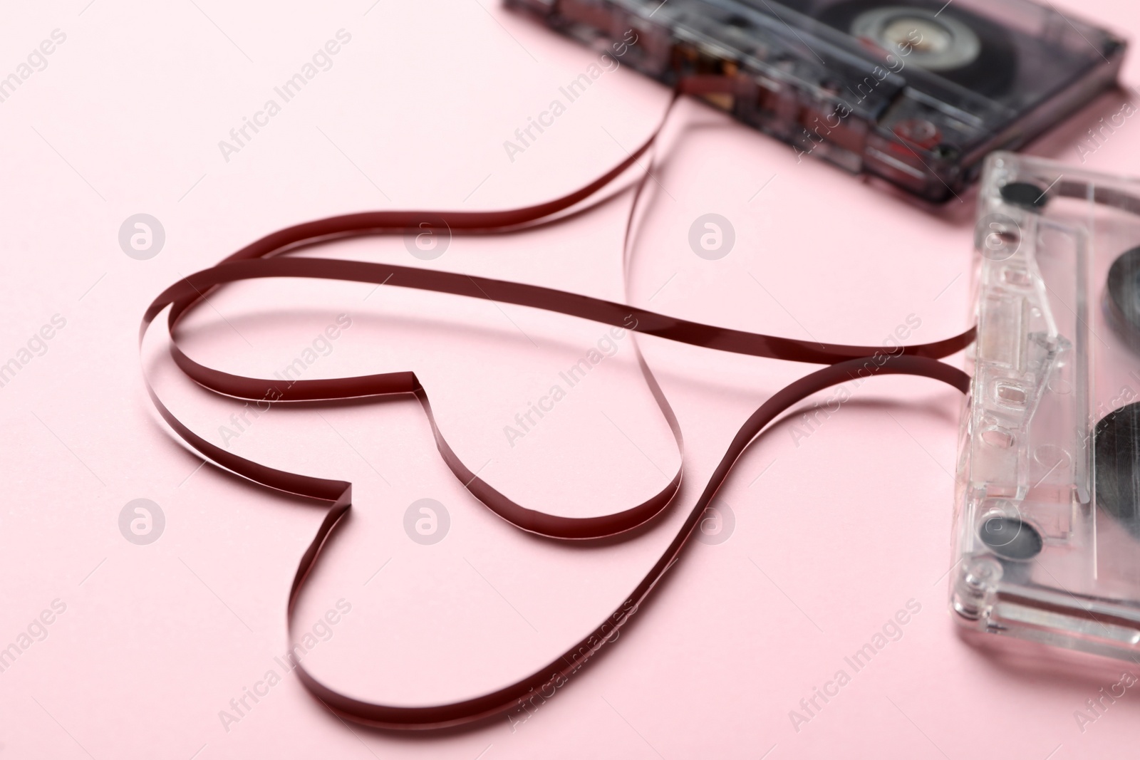 Photo of Music cassettes and hearts made of tape on pink background, closeup. Listening love songs