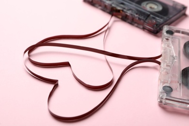 Photo of Music cassettes and hearts made of tape on pink background, closeup. Listening love songs
