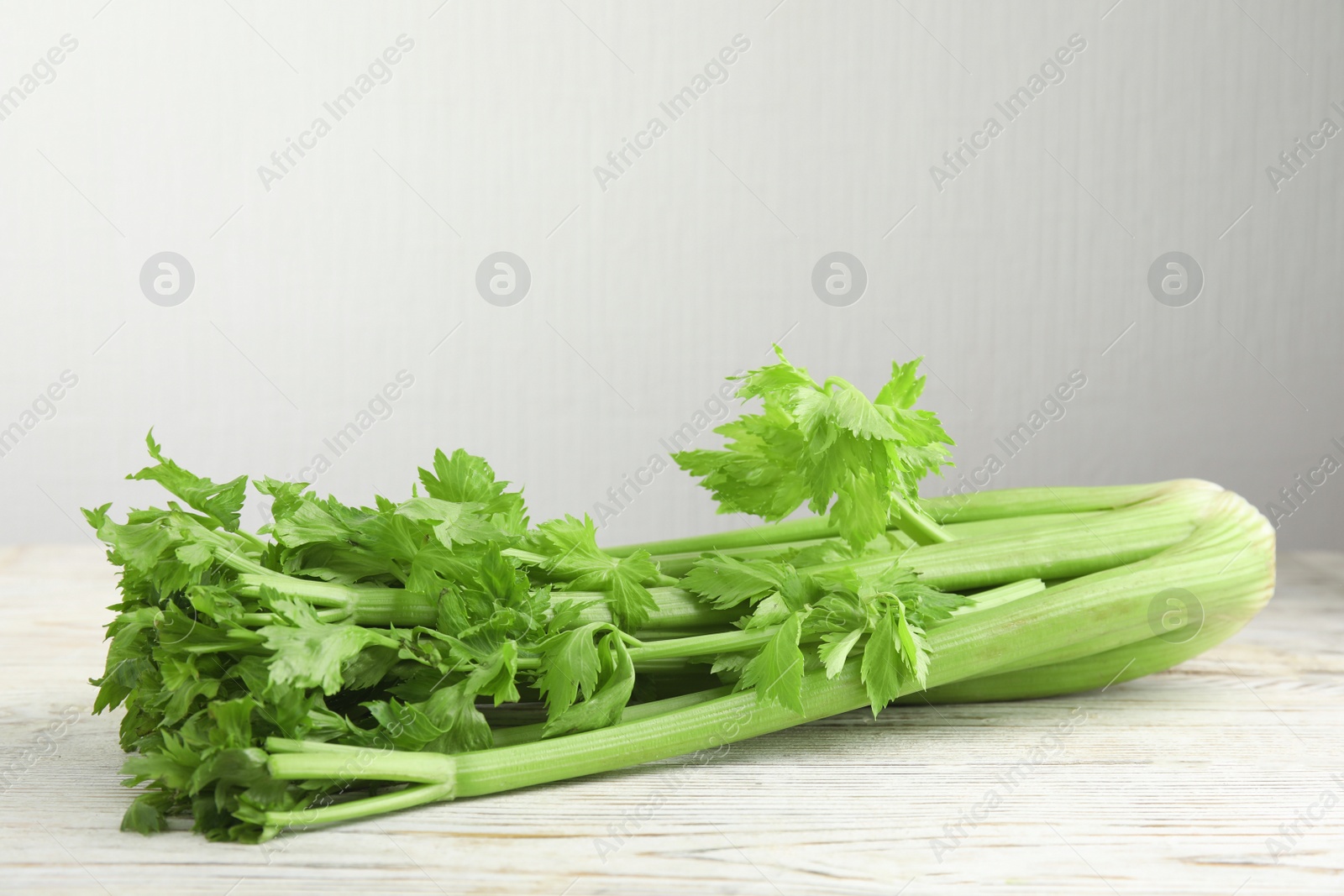 Photo of Fresh ripe green celery on white wooden table