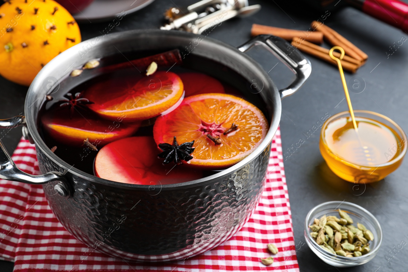 Photo of Delicious mulled wine and ingredients on grey table, closeup