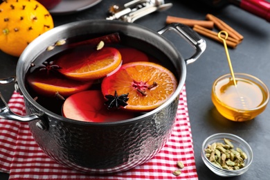 Delicious mulled wine and ingredients on grey table, closeup