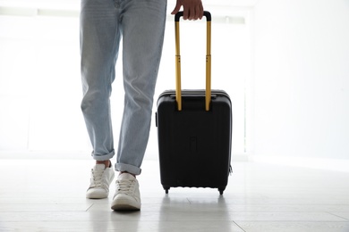 Man with black travel suitcase in airport