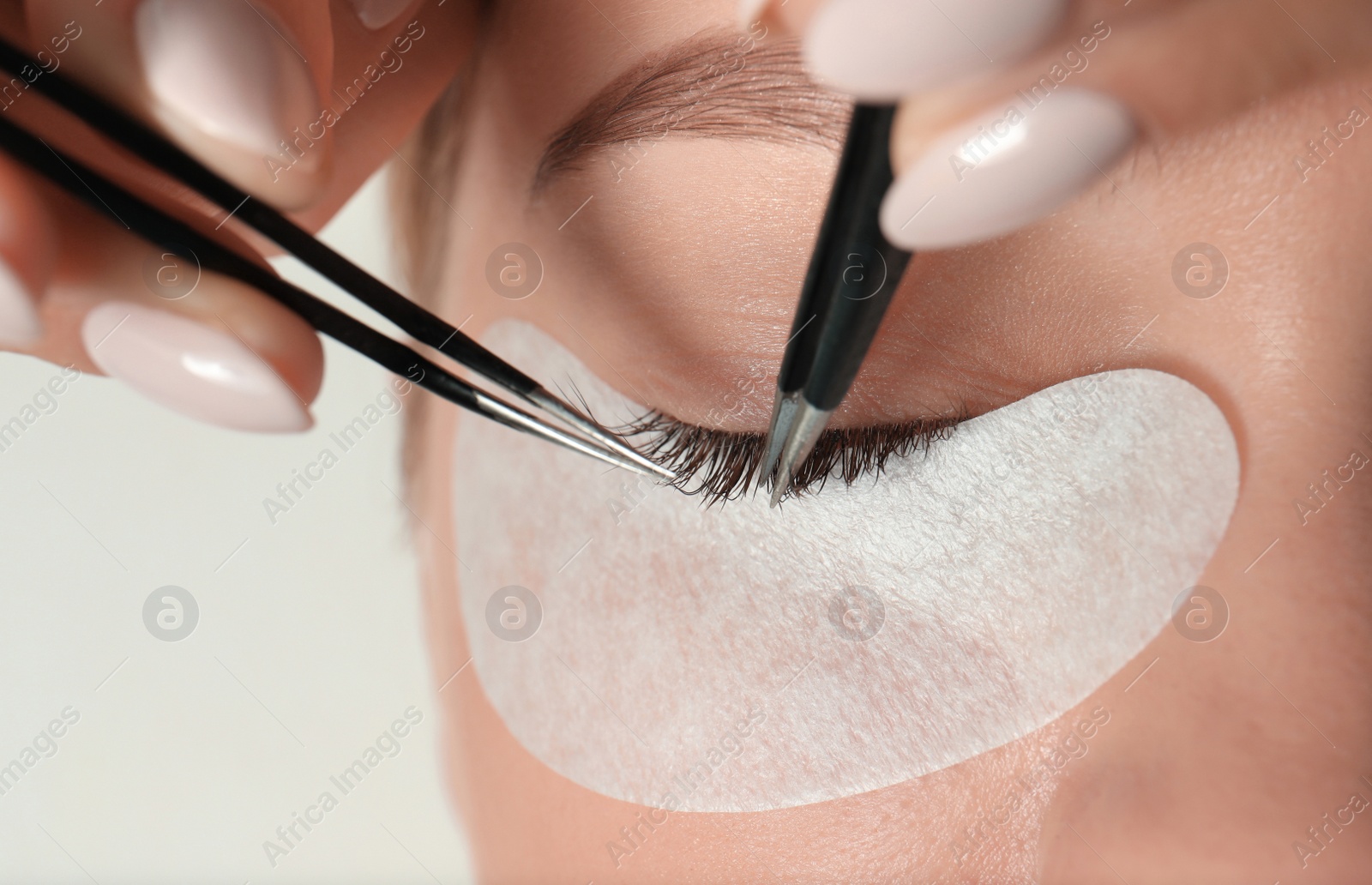 Photo of Young woman undergoing eyelash extension procedure, closeup