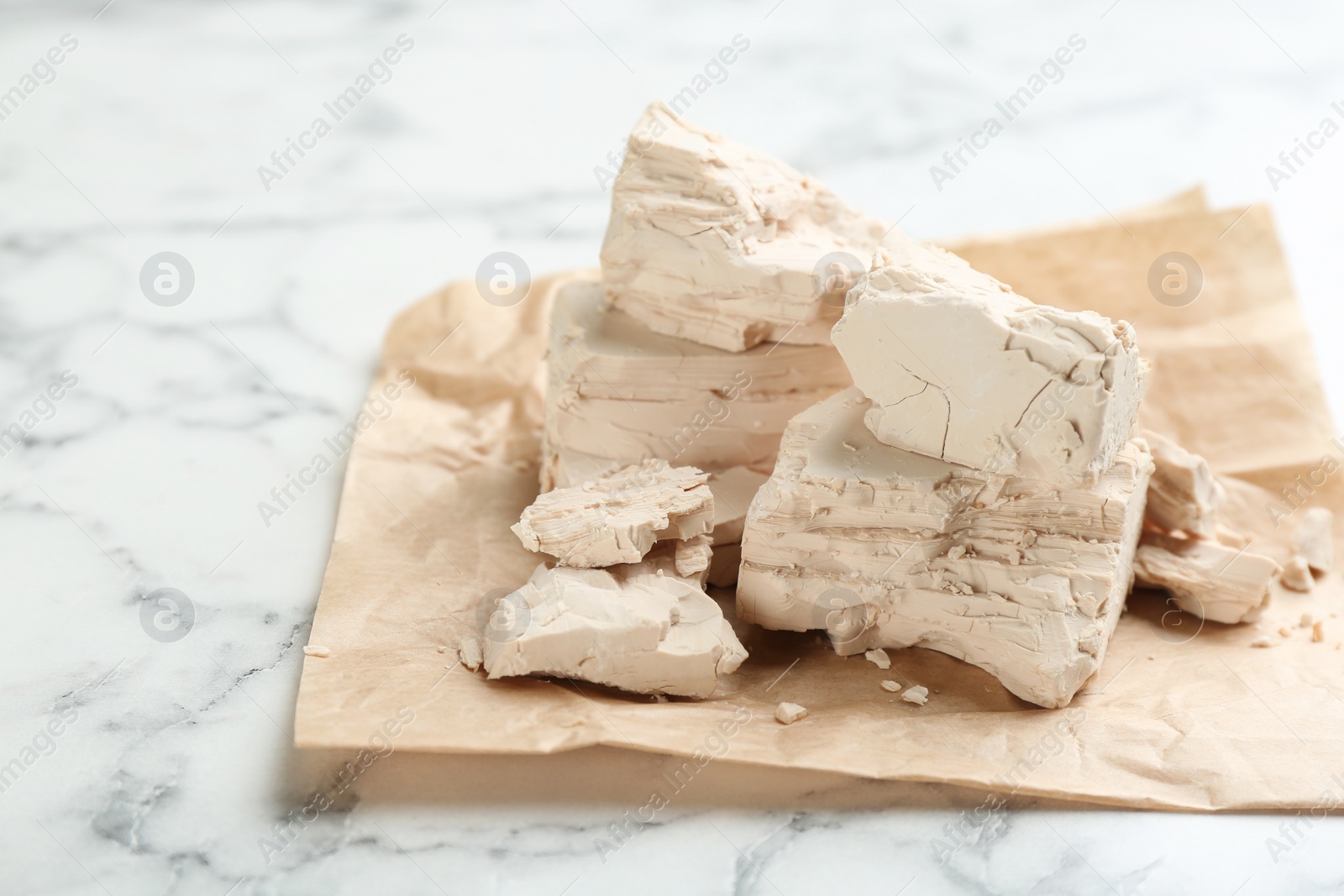 Photo of Pieces of compressed yeast on white marble table, closeup