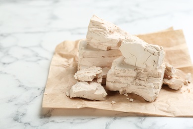 Pieces of compressed yeast on white marble table, closeup