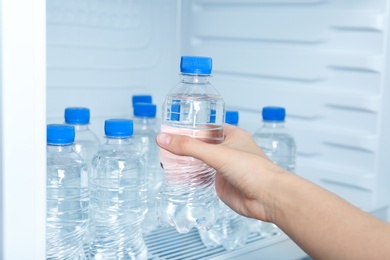 Photo of Woman taking bottle of water from refrigerator, closeup