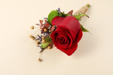Photo of Stylish boutonniere with red rose on beige background, closeup