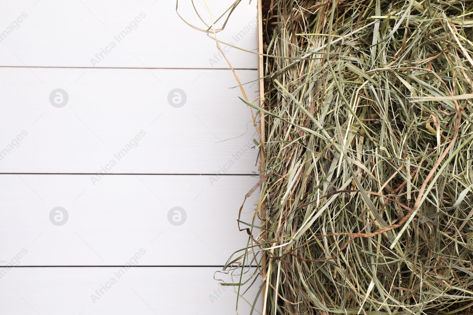 Photo of Heap of dried hay on white wooden table, top view. Space for text