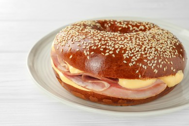 Photo of Delicious bagel with ham and cheese on white wooden table, closeup