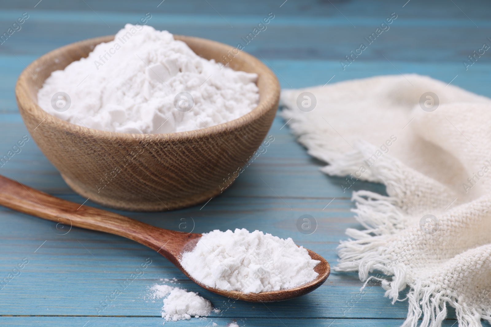 Photo of Bowl and spoon of natural starch on light blue wooden table