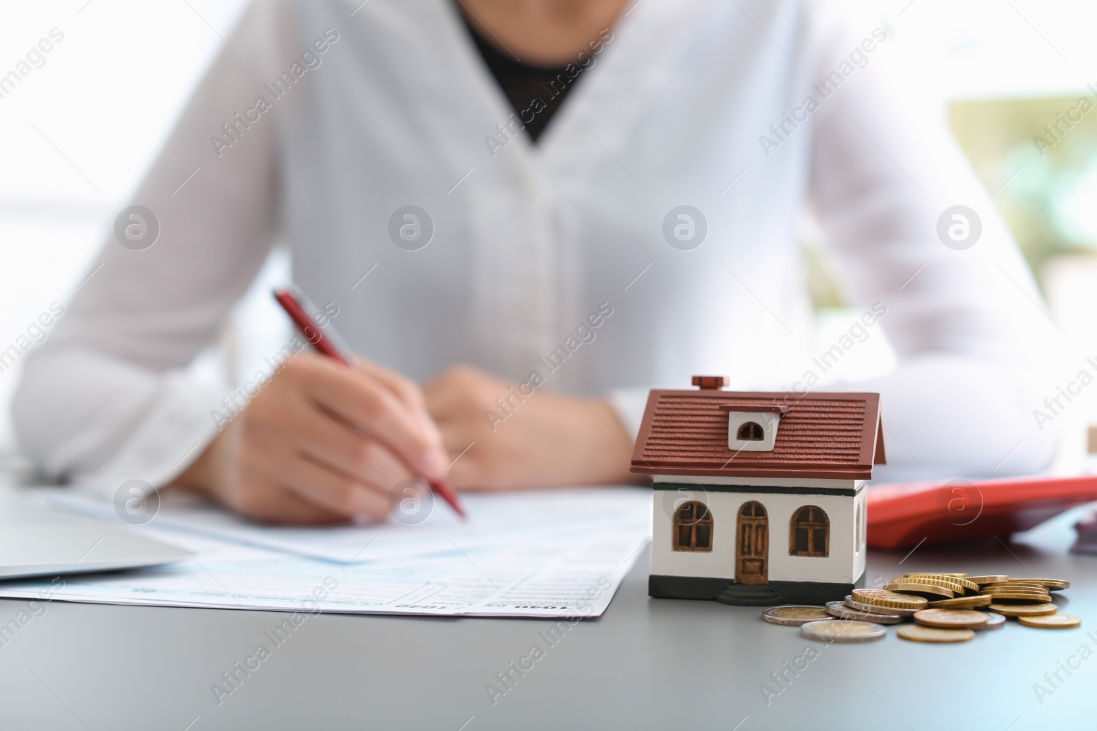 Photo of House model, coins and blurred woman on background. Tax day