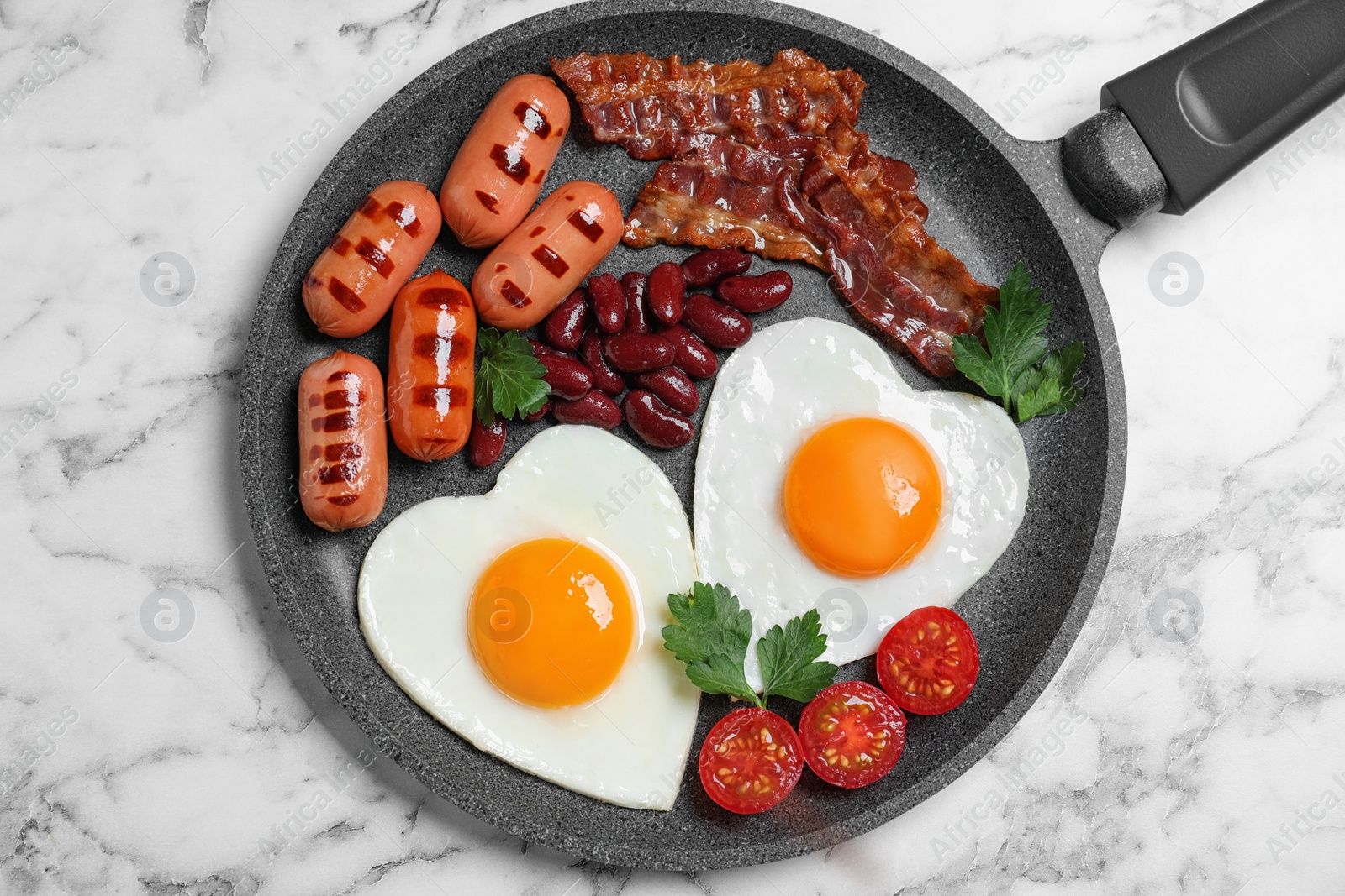 Photo of Delicious breakfast with heart shaped fried eggs and  sausages on white marble table, top view