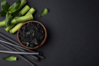 Photo of Fresh bamboo and charcoal on black background, flat lay. Space for text