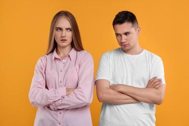 Photo of Portrait of resentful couple with crossed arms on orange background