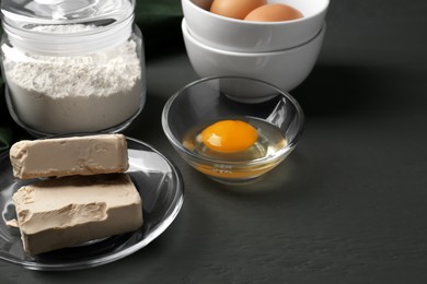 Photo of Compressed yeast, eggs and flour on grey wooden table, space for text