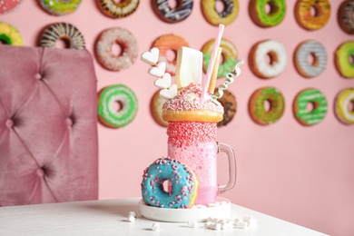 Mason jar of tasty milk shake with sweets on table in cafe