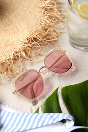 Photo of Stylish sunglasses and beach accessories on sand