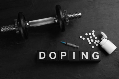 Photo of Wooden cubes with word Doping, dumbbell and drugs on black background, flat lay